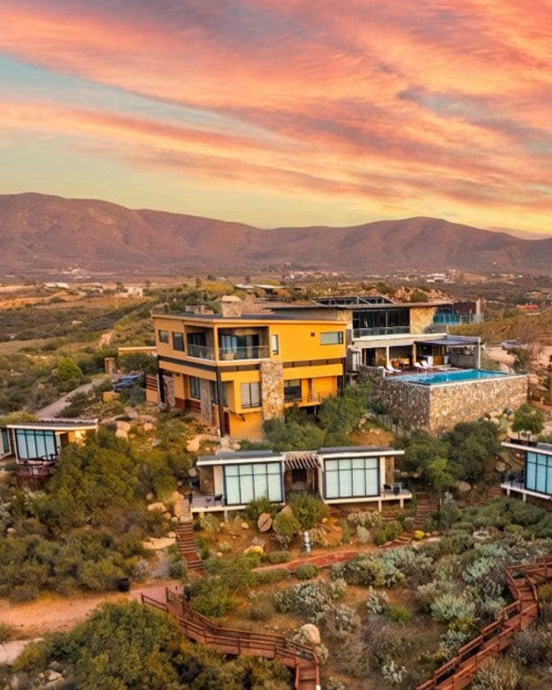Vista aérea de Contemplación Resort & Spa al atardecer, con cabañas sobre la colina frente a las montañas del Valle de Guadalupe